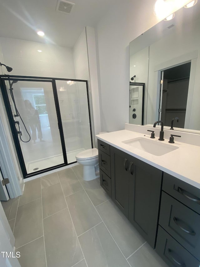 bathroom with vanity, a shower stall, toilet, and visible vents