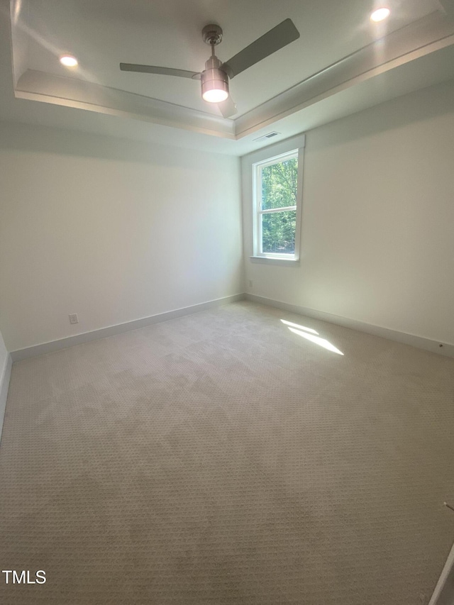 empty room featuring ceiling fan, baseboards, light carpet, a tray ceiling, and recessed lighting