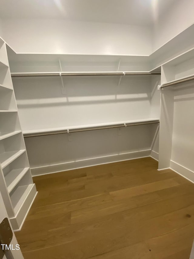 walk in closet with wood finished floors