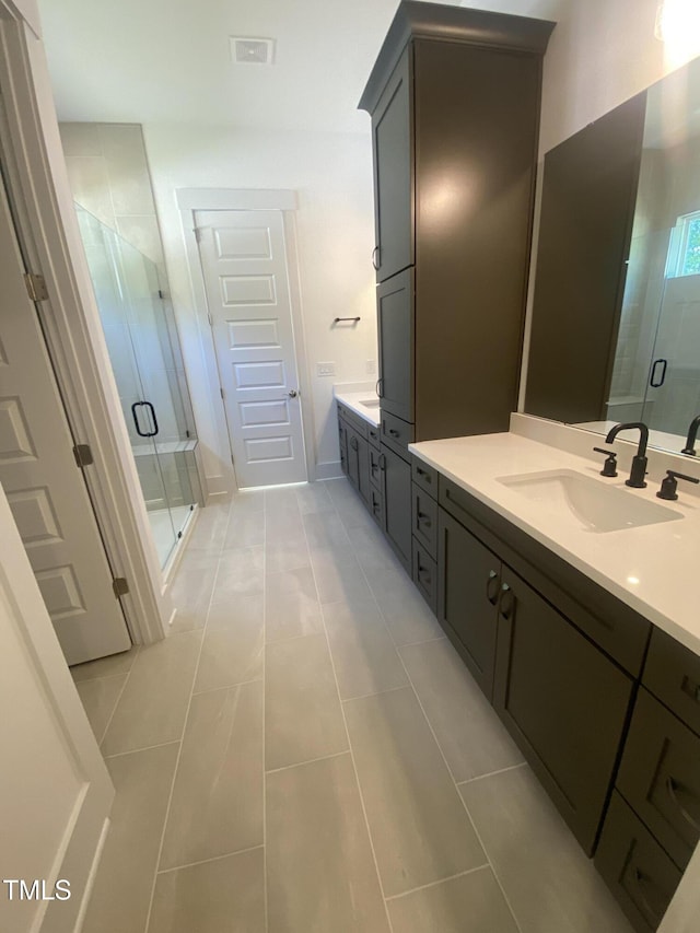 bathroom with tile patterned flooring, a sink, a stall shower, and two vanities