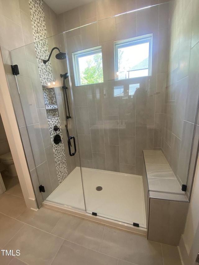 full bathroom featuring tile patterned flooring, toilet, and a shower stall