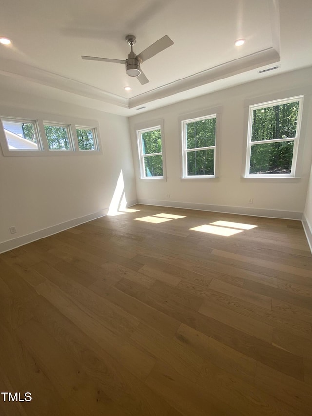 empty room with ceiling fan, wood finished floors, a raised ceiling, baseboards, and recessed lighting