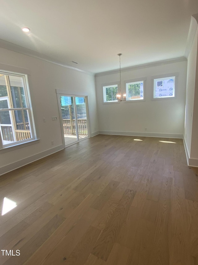 unfurnished dining area with baseboards, ornamental molding, wood finished floors, and a chandelier
