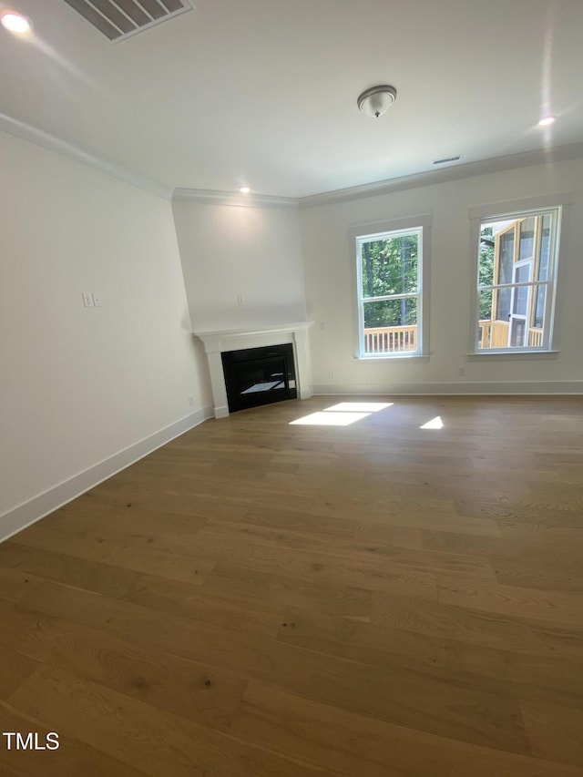 unfurnished living room with visible vents, ornamental molding, wood finished floors, a fireplace, and baseboards