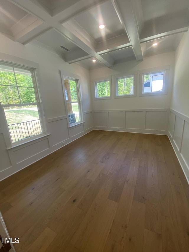 unfurnished room with beam ceiling, a decorative wall, hardwood / wood-style floors, a wainscoted wall, and coffered ceiling