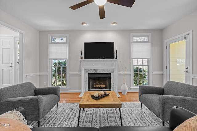 living room with ceiling fan, wood finished floors, and a high end fireplace