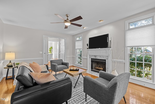 living area featuring a fireplace, light wood finished floors, recessed lighting, ceiling fan, and baseboards