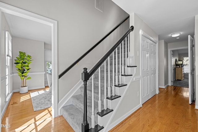 stairway with a wealth of natural light, baseboards, and hardwood / wood-style floors