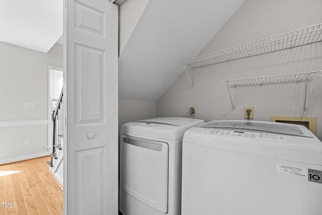 laundry area with washing machine and dryer, laundry area, light wood-style flooring, and baseboards