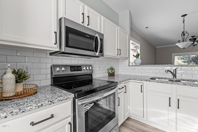 kitchen featuring white cabinets, ornamental molding, stainless steel appliances, and a sink