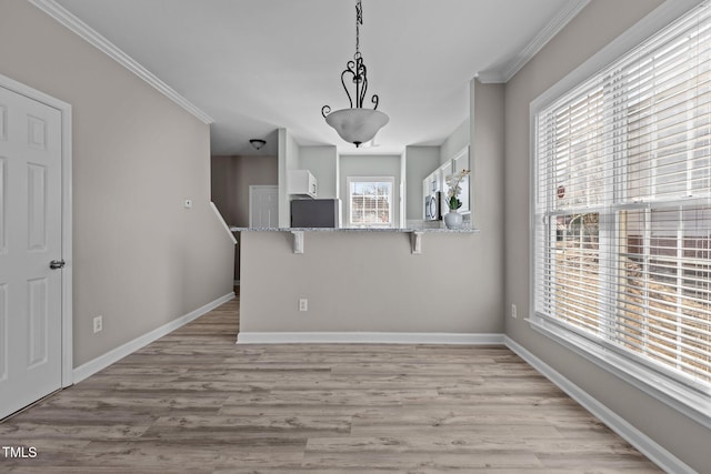 spare room with light wood finished floors, baseboards, and ornamental molding