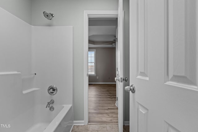 bathroom featuring  shower combination, tile patterned flooring, and baseboards