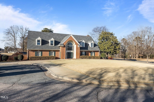 cape cod home featuring brick siding