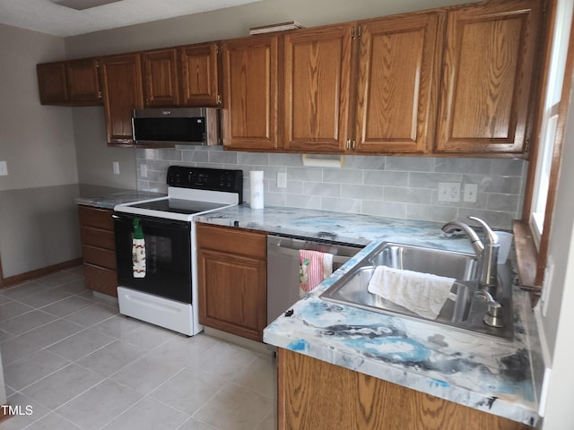 kitchen featuring appliances with stainless steel finishes, light tile patterned floors, sink, and tasteful backsplash