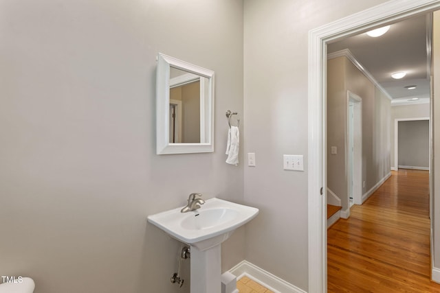 bathroom featuring hardwood / wood-style floors, crown molding, and sink