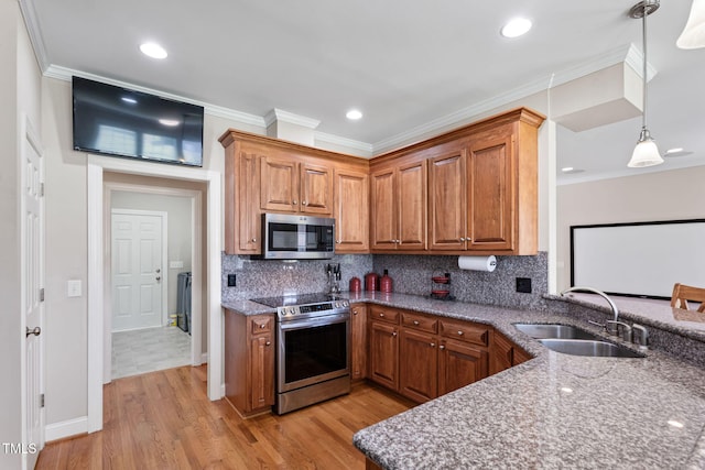 kitchen with sink, light stone countertops, stainless steel appliances, and decorative light fixtures