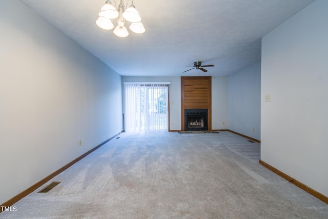 unfurnished living room with ceiling fan with notable chandelier, carpet flooring, and a large fireplace