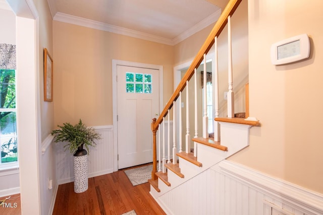 entrance foyer with a wainscoted wall, crown molding, stairway, and wood finished floors