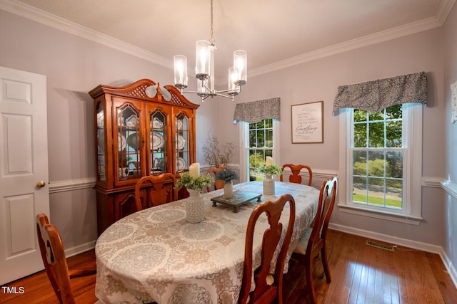 dining space with an inviting chandelier, wood-type flooring, visible vents, and crown molding