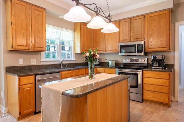 kitchen featuring pendant lighting, crown molding, appliances with stainless steel finishes, a sink, and a kitchen island