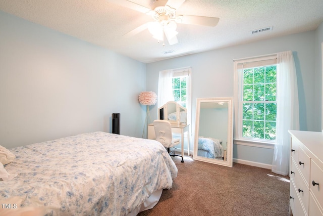 bedroom with a textured ceiling, ceiling fan, visible vents, baseboards, and carpet