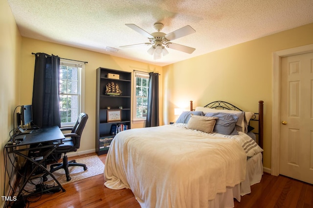 bedroom featuring a ceiling fan, a textured ceiling, baseboards, and wood finished floors