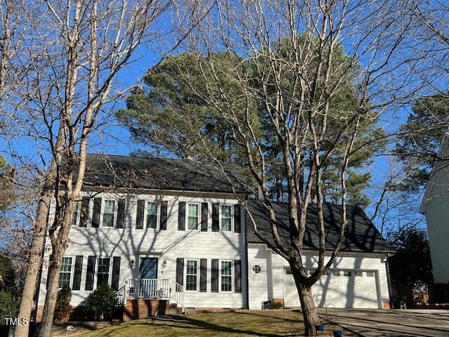 colonial inspired home with a garage, driveway, a front lawn, and crawl space