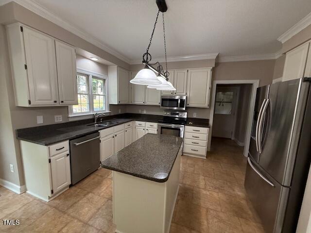 2006 Chedington Dr, Apex, NC 27502 - kitchen with appliances with stainless steel finishes, dark countertops, crown molding, a kitchen island, and white cabinetry