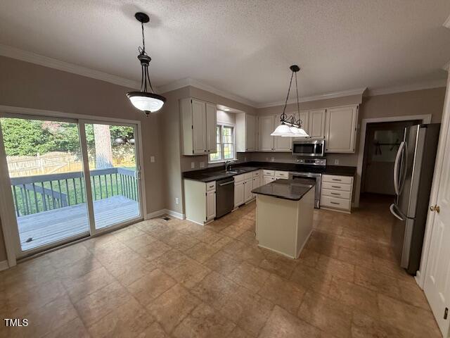2006 Chedington Dr, Apex, NC 27502 - kitchen with stainless steel appliances, dark countertops, a center island, white cabinets, and pendant lighting