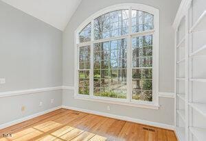 interior space featuring lofted ceiling, plenty of natural light, wood finished floors, and baseboards