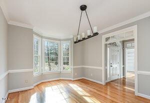 unfurnished dining area featuring ornamental molding, wood finished floors, and baseboards