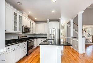 kitchen with stainless steel appliances, dark countertops, glass insert cabinets, and light wood-style flooring