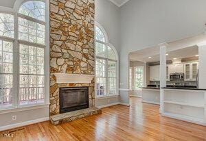 unfurnished living room with a high ceiling, a fireplace, wood finished floors, and baseboards