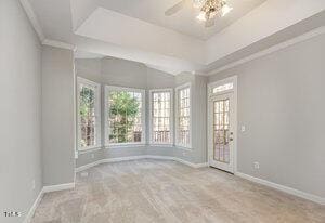 empty room with crown molding, plenty of natural light, baseboards, and a ceiling fan