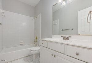 bathroom with tile patterned floors, bathing tub / shower combination, toilet, and vanity