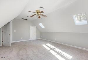 bonus room with carpet floors, lofted ceiling with skylight, ceiling fan, and baseboards