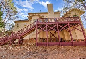 back of property featuring a deck, stairway, and a chimney