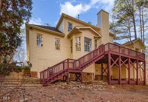 rear view of property with a chimney, stairway, and a deck