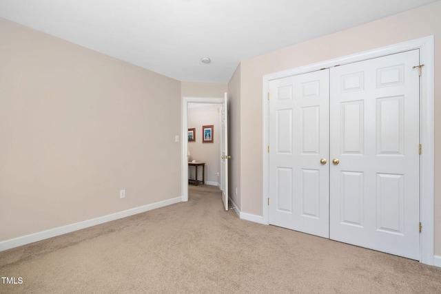 unfurnished bedroom featuring light carpet, a closet, and baseboards