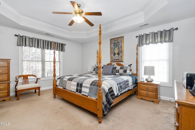 bedroom with a tray ceiling, multiple windows, visible vents, and light colored carpet