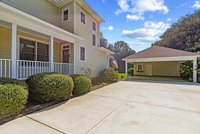 view of property exterior with driveway, covered porch, and a carport