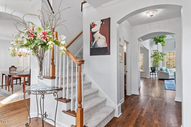 stairs featuring ornamental molding, arched walkways, and wood finished floors