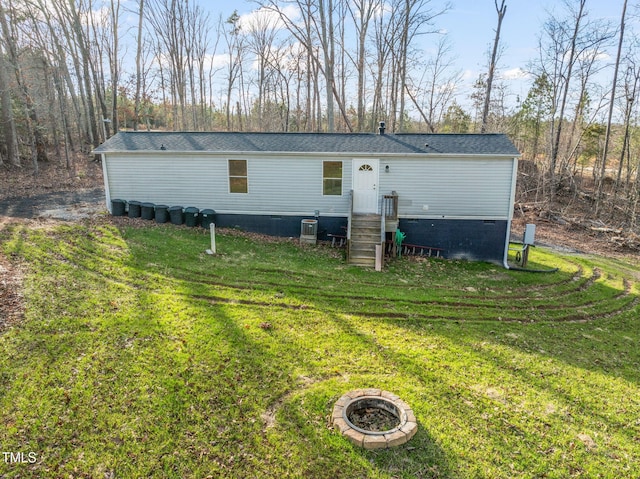 exterior space with central air condition unit, a front lawn, and an outdoor fire pit