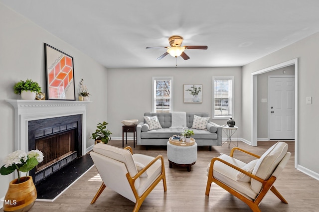 living room with a fireplace, light wood-style flooring, and baseboards