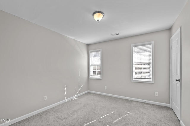 spare room featuring carpet, visible vents, and baseboards