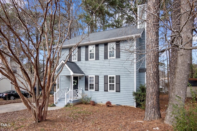 colonial-style house featuring roof with shingles