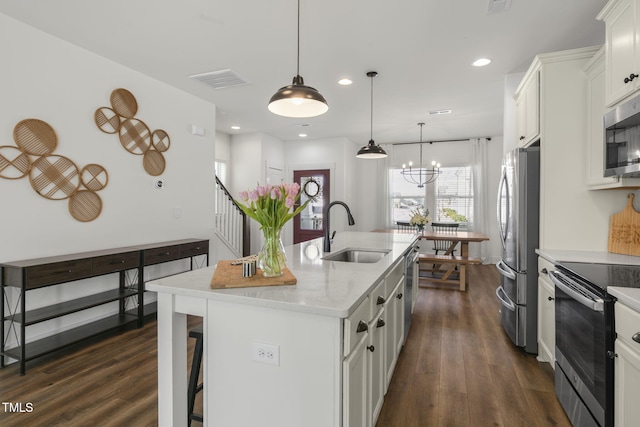 kitchen featuring a kitchen island with sink, appliances with stainless steel finishes, dark wood-type flooring, and a sink