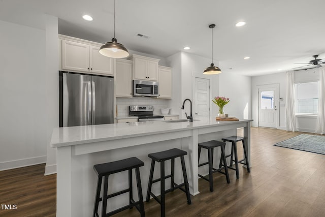 kitchen featuring tasteful backsplash, visible vents, dark wood finished floors, appliances with stainless steel finishes, and a sink