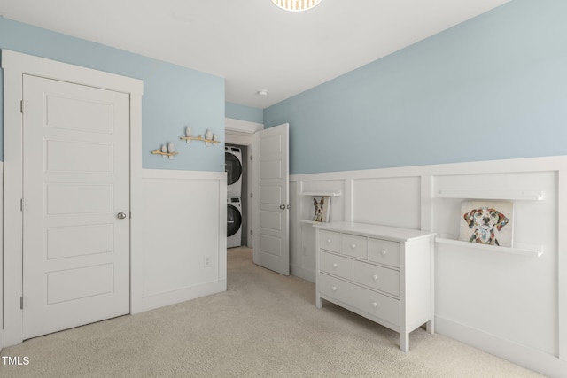 bedroom featuring carpet flooring, wainscoting, and stacked washing maching and dryer