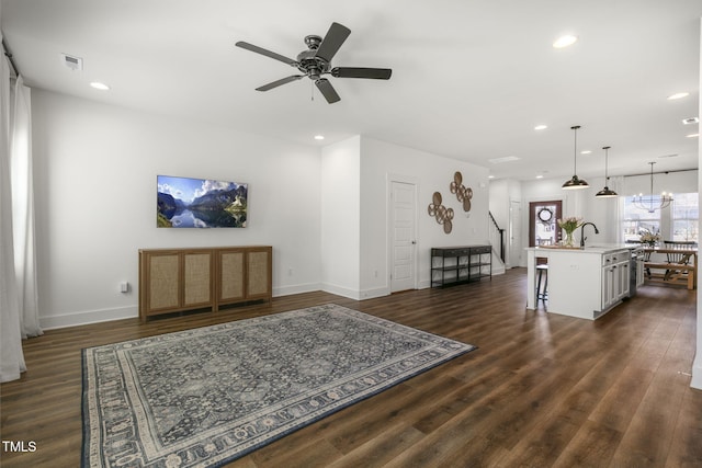 living area with ceiling fan with notable chandelier, baseboards, dark wood-type flooring, and recessed lighting